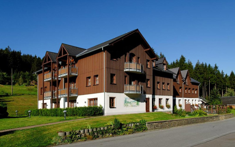 Hotel Schwarzbeerschänke in Pobershau – gemütliches Erzgebirgshotel mit Tradition, Natur und Genuss Außenansicht des Hotels Schwarzbeerschänke in Pobershau mit traditioneller Architektur, umgeben von Wald und Hügellandschaft im Erzgebirge
